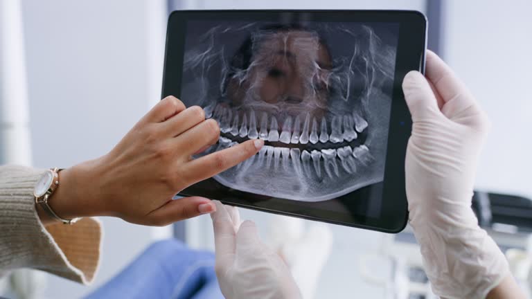 Dentist and patient reviewing a panoramic dental X-ray together on a tablet