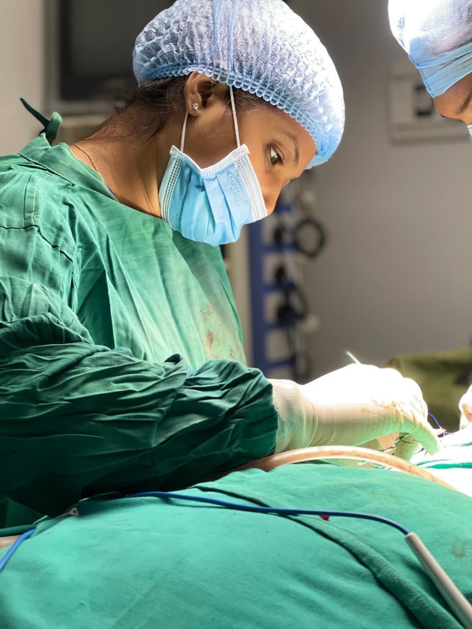 Dr. Krishna Kotadiya Shah performing a surgical procedure in full theatre scrubs